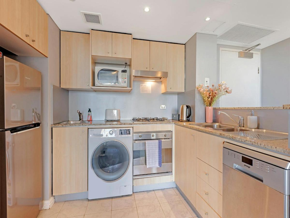 Fully equipped kitchen with cooktop, oven, microwave, washing machine, and ample cabinetry.