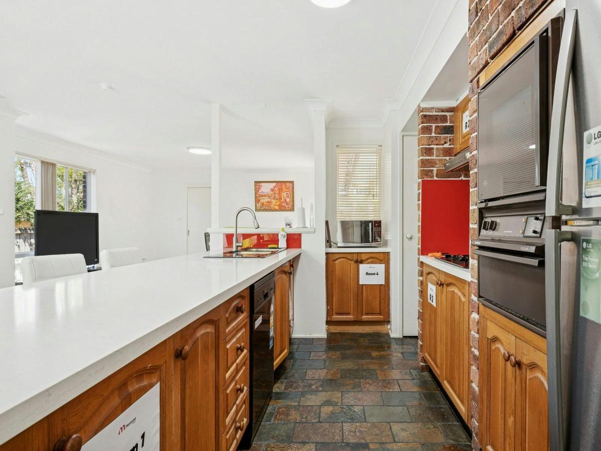 Shared kitchen with long countertop, wooden cabinetry, and cooking appliances.
