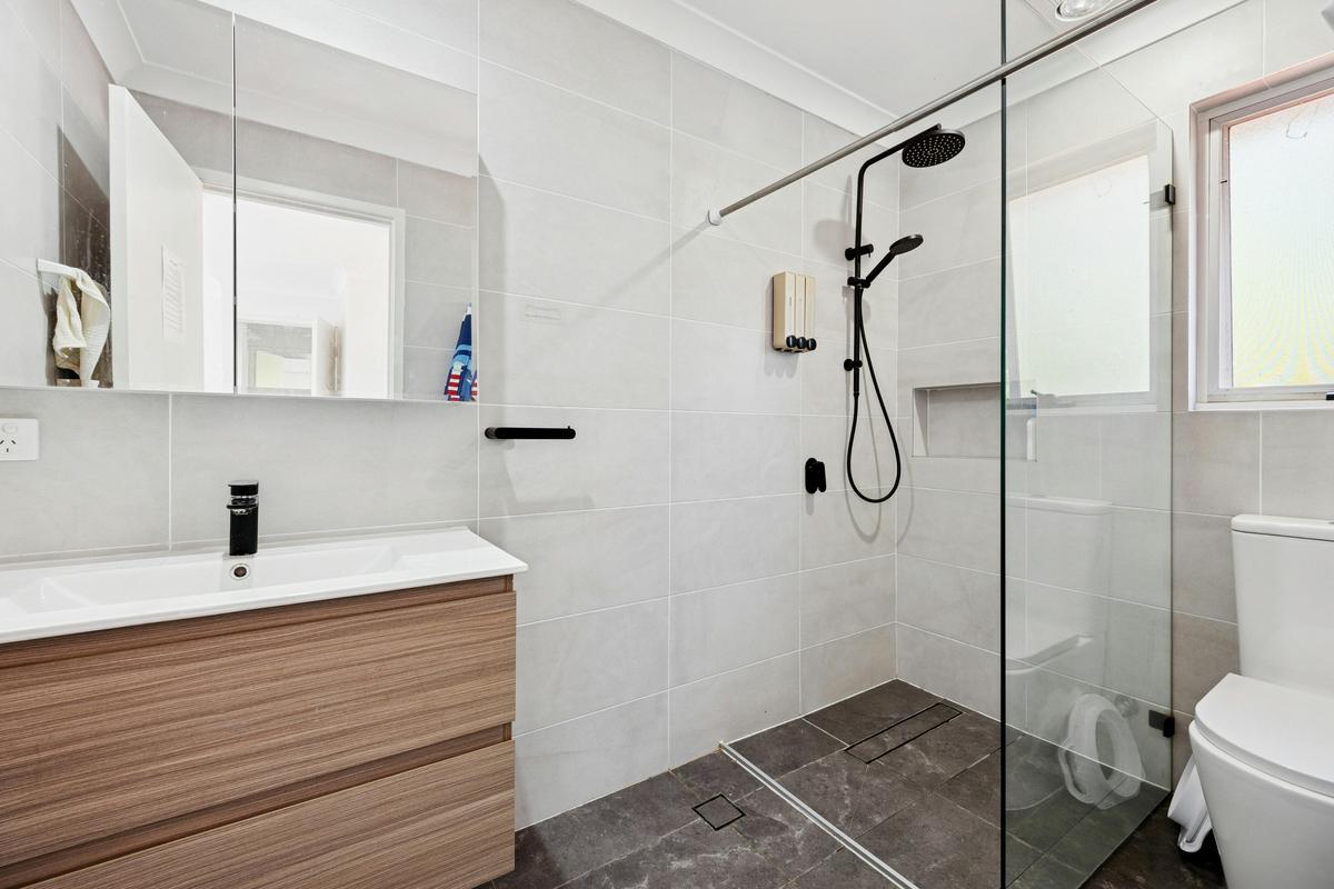 Modern bathroom with vanity, toilet, and glass-enclosed shower.