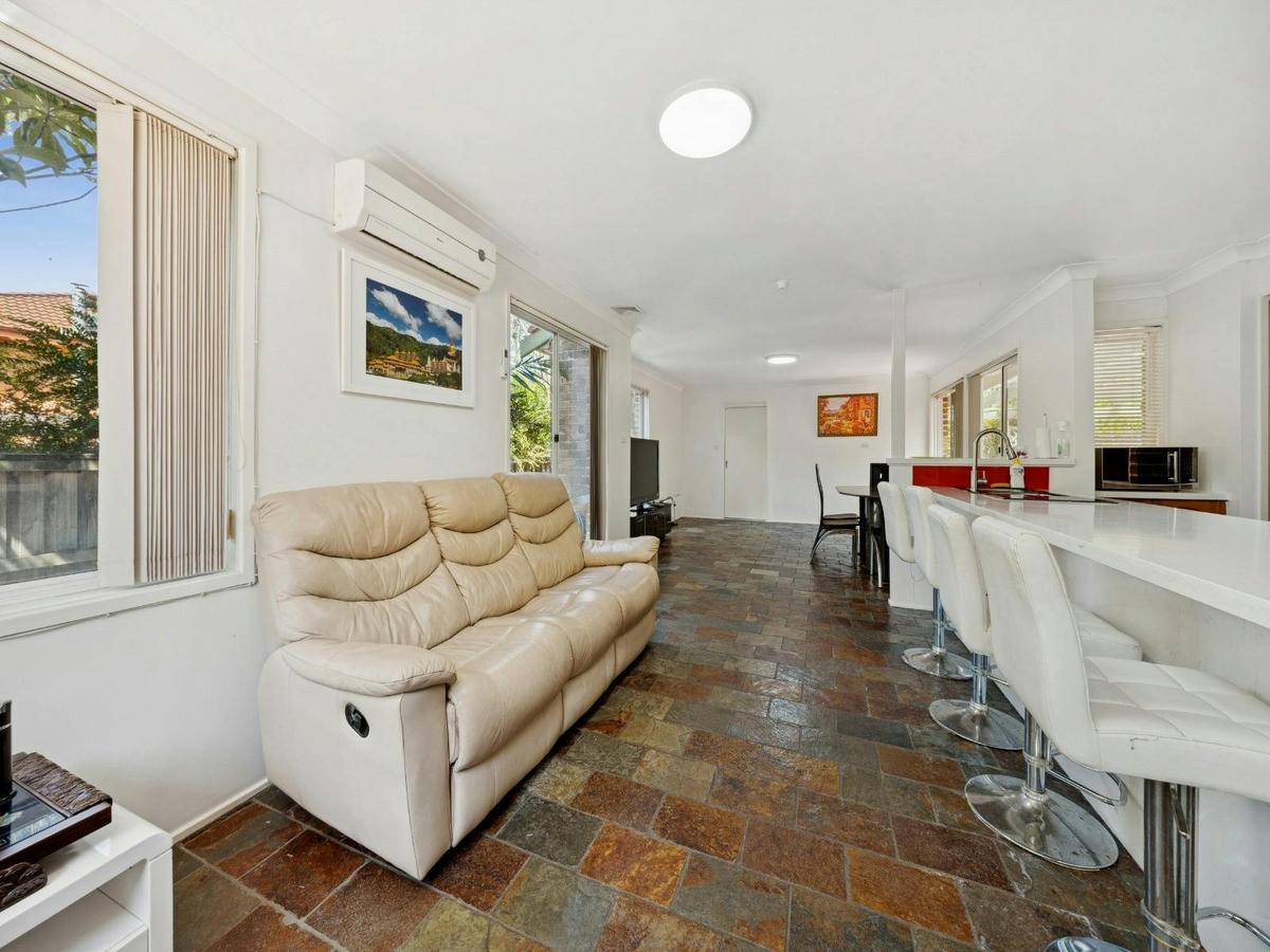 Open-plan living area with sofa seating and adjoining kitchen space.