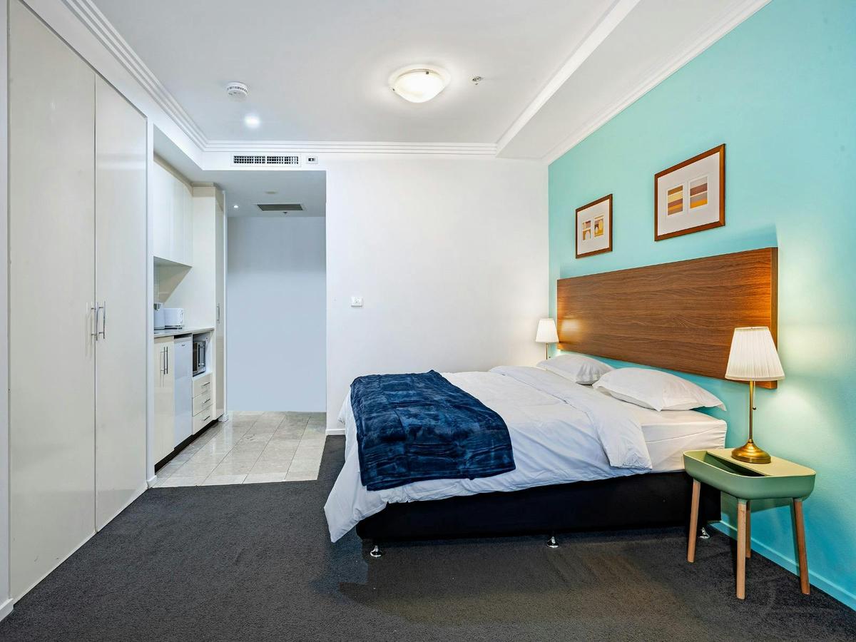 Spacious studio featuring a comfortable king bed, bedside tables with lamps, and wall art