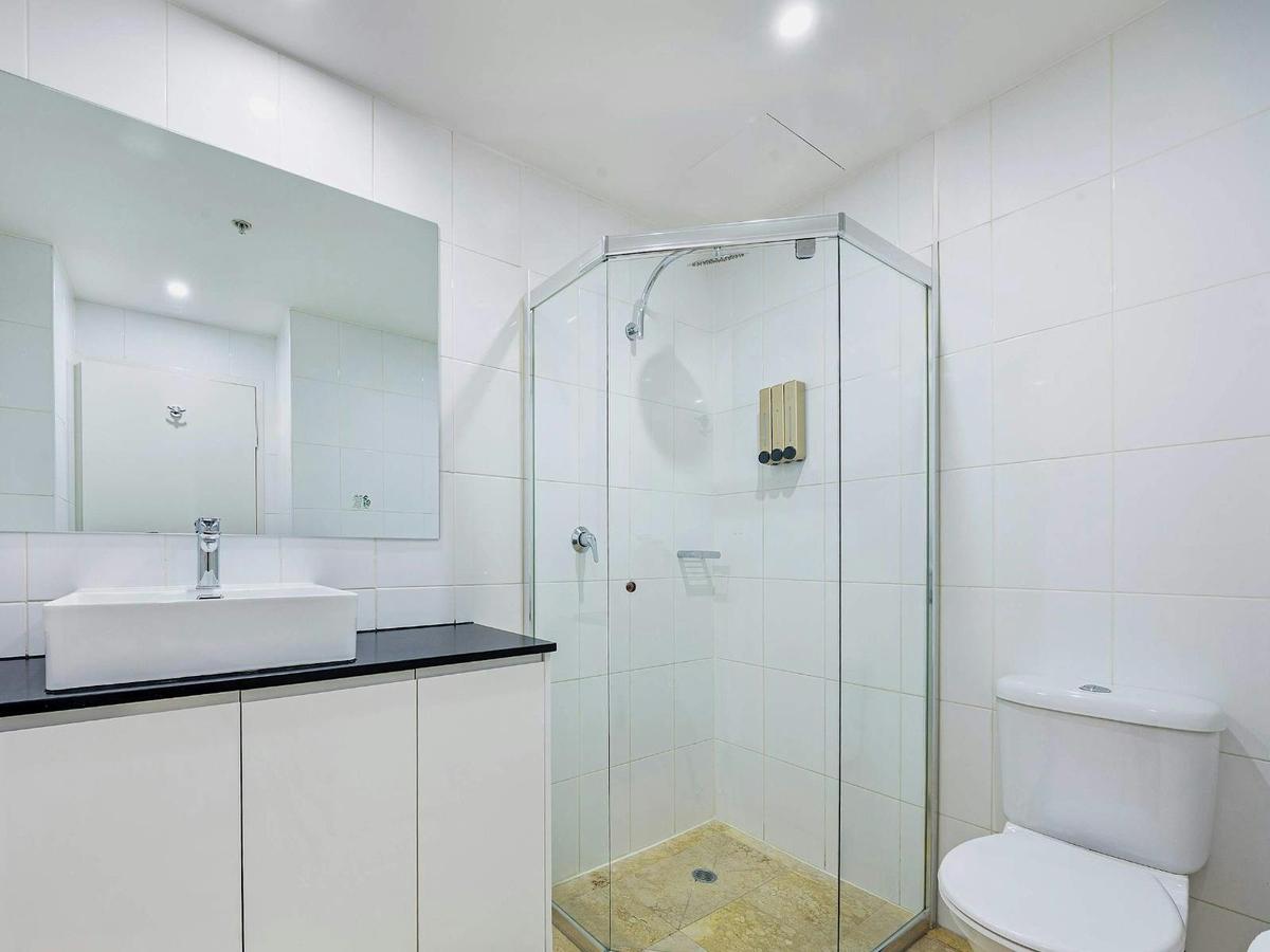 Modern bathroom with glass shower enclosure, vanity with storage, and toilet.