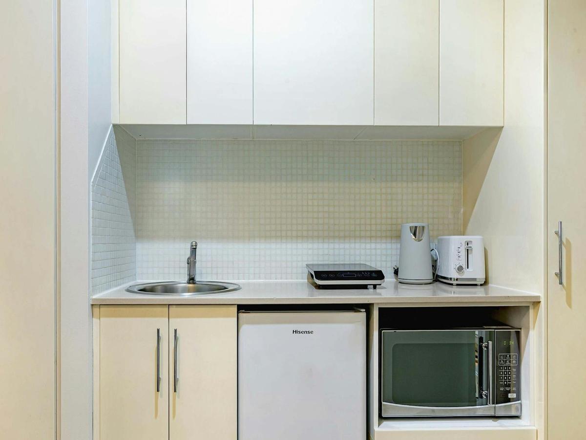 Compact kitchenette with sink, microwave, bar fridge, cabinetry, and tea/coffee facilities.