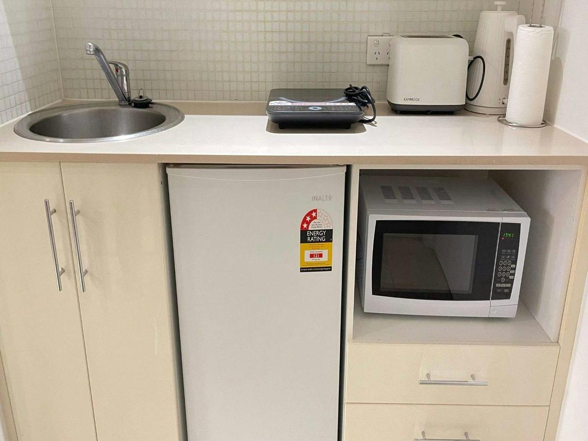 Kitchenette with microwave, bar fridge, cabinetry, and tea/coffee facilities.
