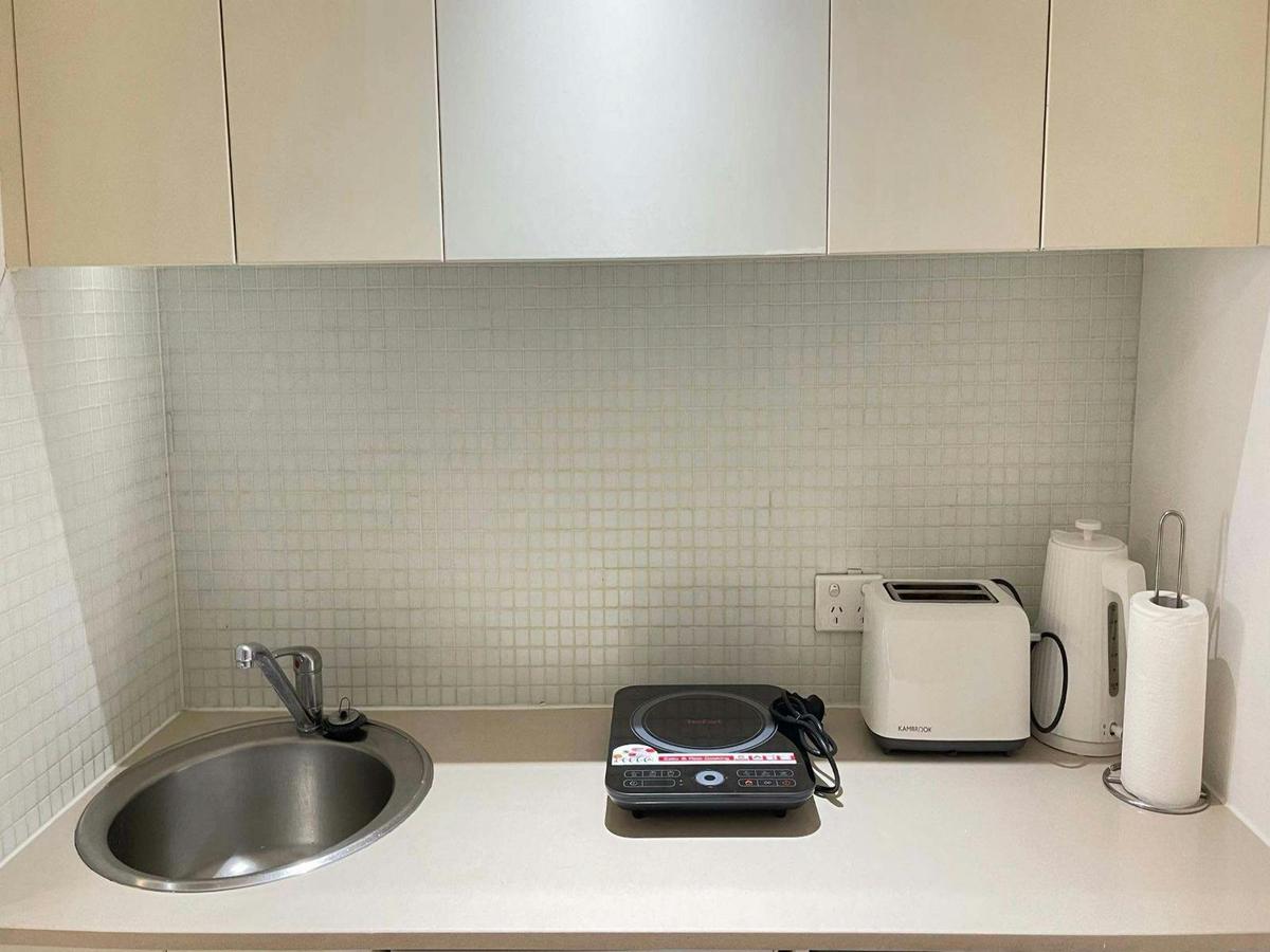 Kitchen counter area with sink, cooktop, kettle, and essential appliances.