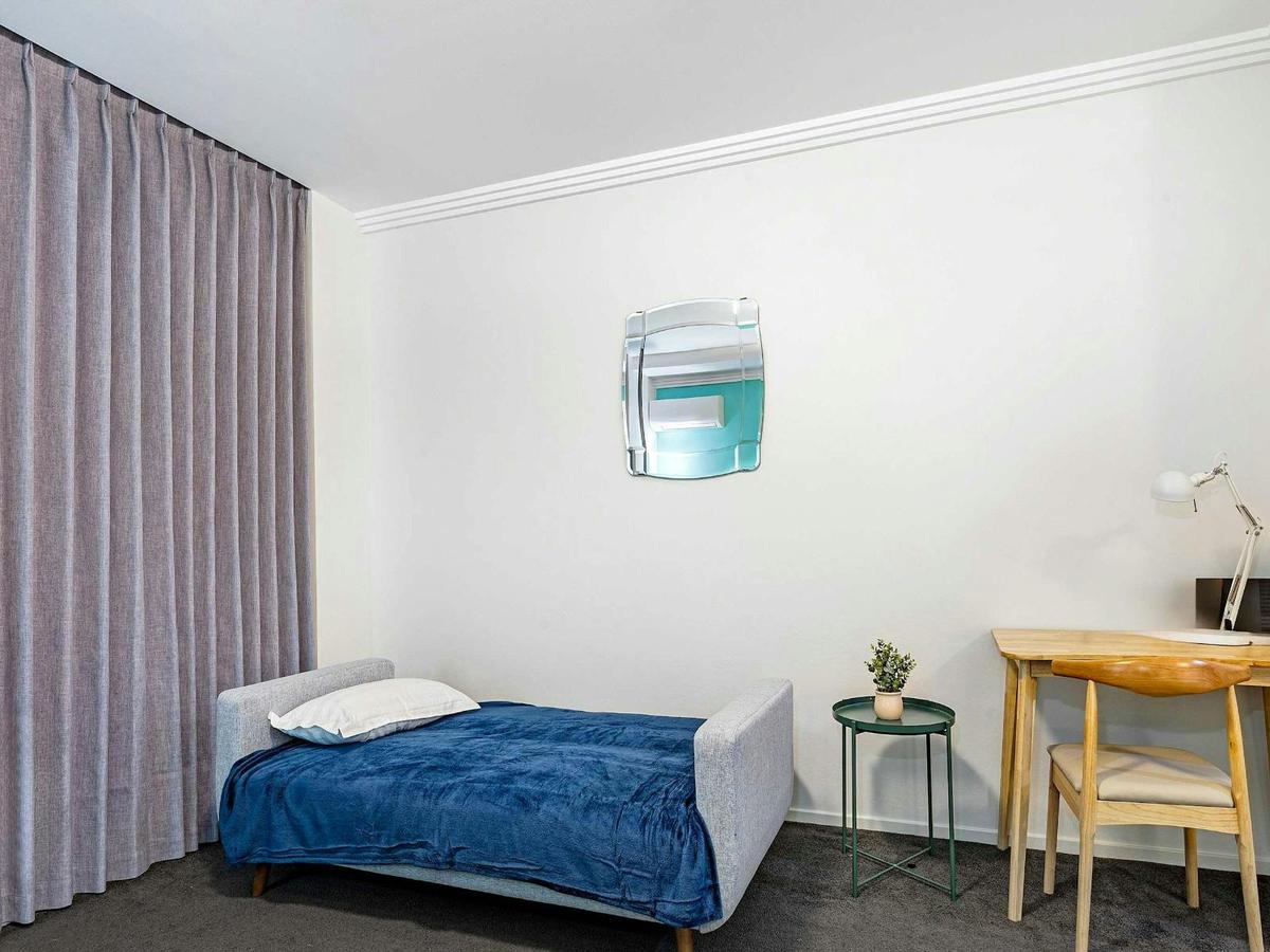 Studio corner with a sofa bed, side table, and floor-to-ceiling curtains.