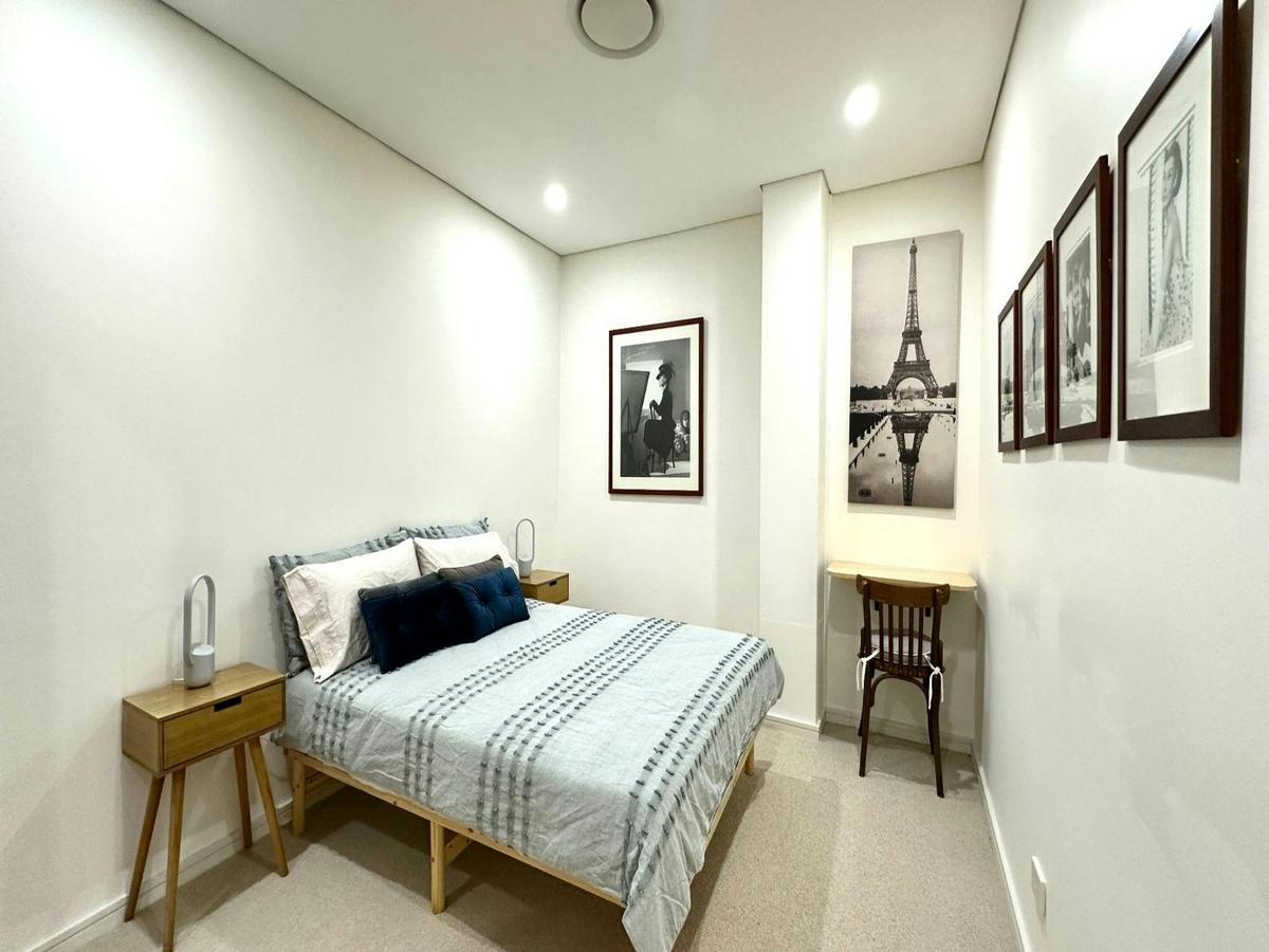 Bedroom featuring a double bed, bedside table, wall art, and study desk.
