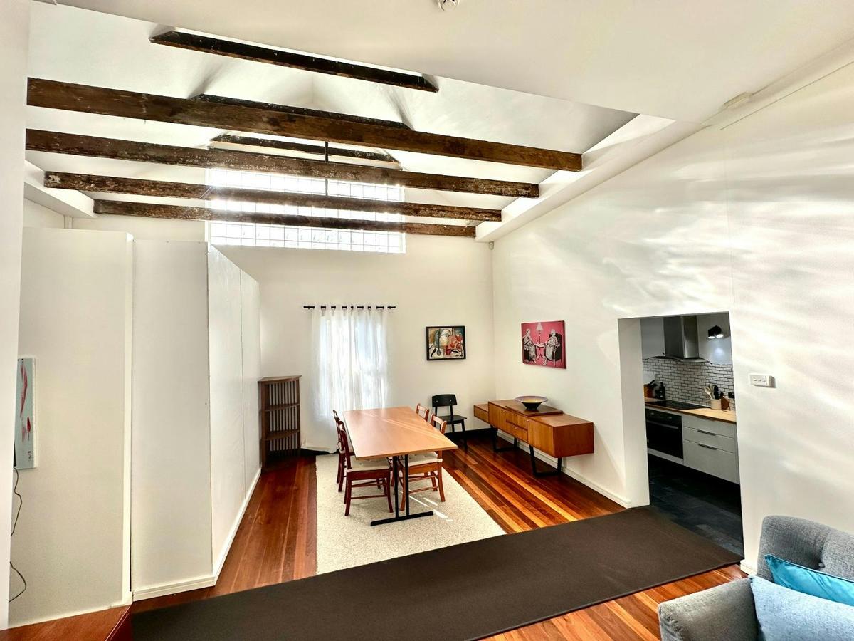 Open-plan living and dining area with timber floors and feature ceiling beams.