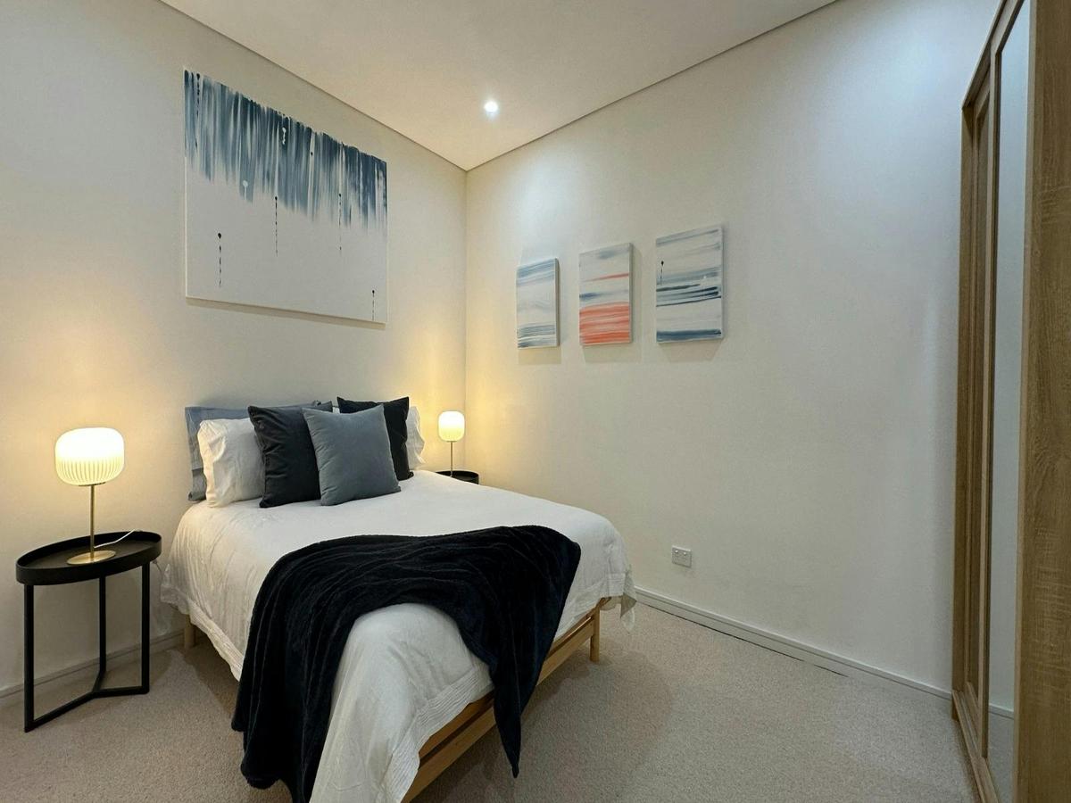 Bedroom styled with double bed, bedside lamps, and minimalist artwork.