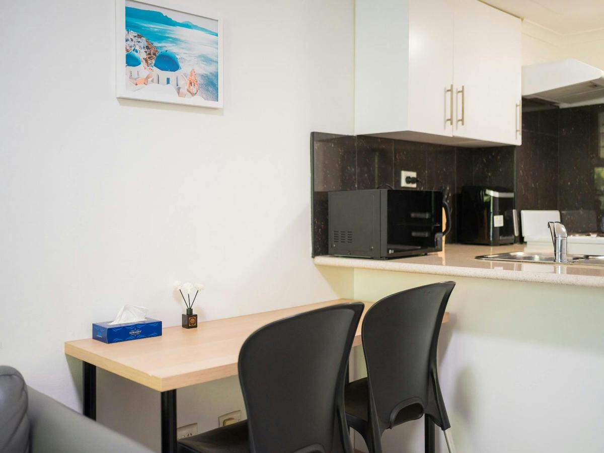 Open-plan kitchen and dining area with breakfast bar, seating for two and modern appliances.