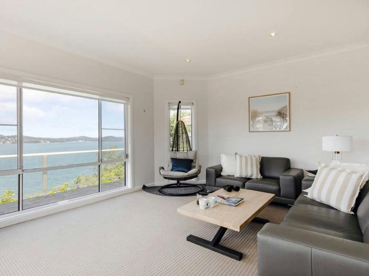 Bright living room with panoramic water views through large windows, comfortable seating and natural