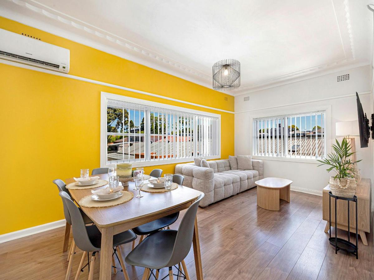 Dining area adjacent to living space with table setting and split system air-conditioning.