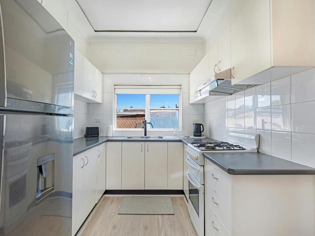 Main kitchen with ample cabinetry, oven, cooktop, and natural light.