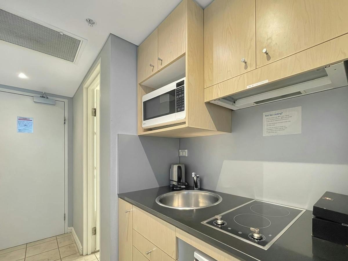 Compact kitchen with cooktop, sink, microwave, and essential appliances.