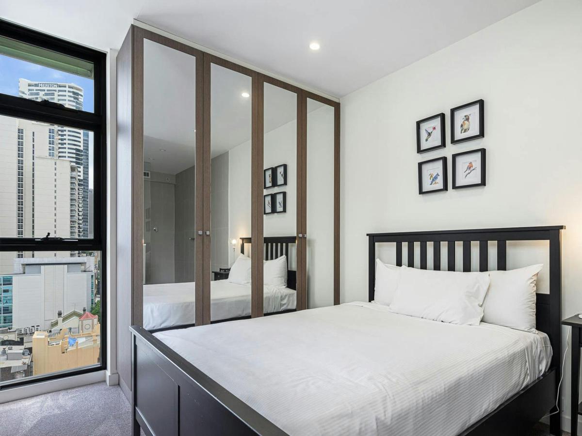 Bedroom featuring a queen-size bed, bedside tables, and balcony access.