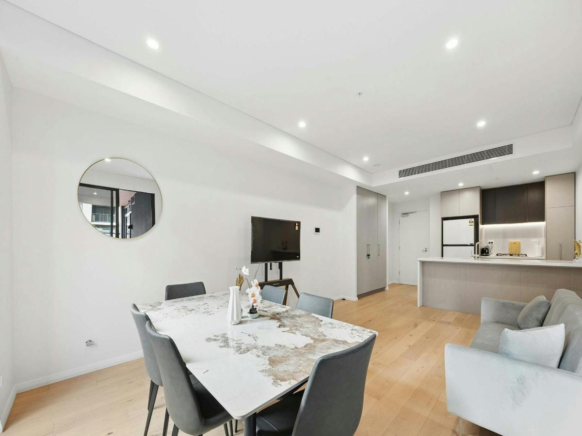 Open-plan living area with dining table, sofa, and modern kitchen.