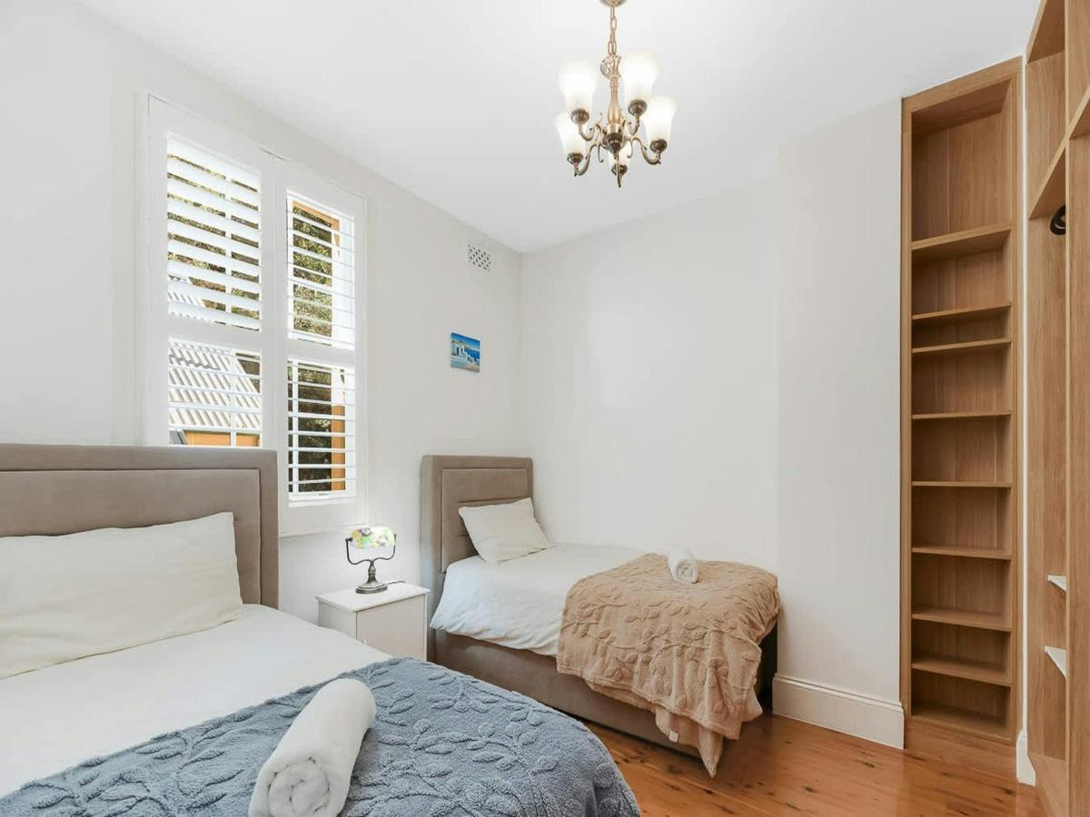 Bright bedroom with double bed, built-in shelving, and plantation shutters