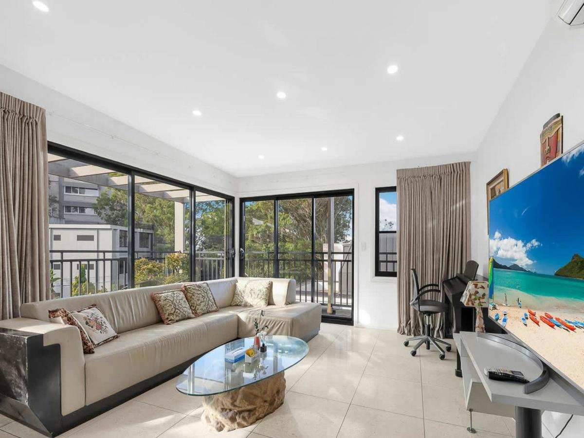 Living area with sofa, Smart TV, and large windows overlooking greenery.