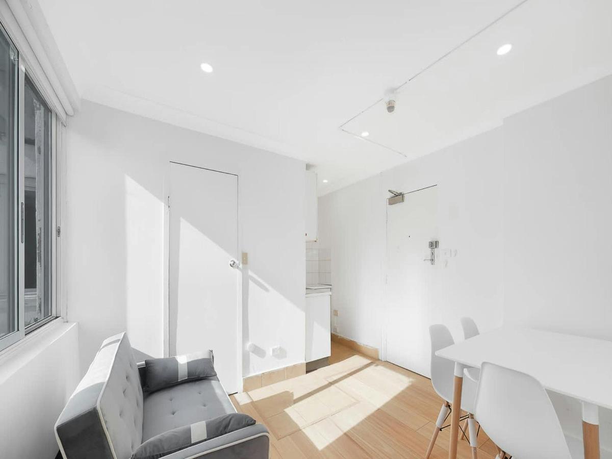 Spacious and sunlit living area with dining setup and a convertible sofa bed