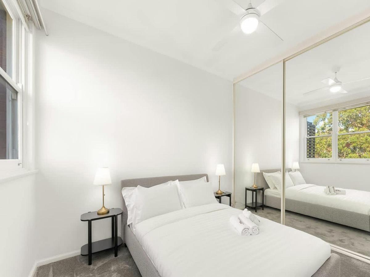 Spacious bedroom featuring a queen bed, wardrobe, and large windows overlooking greenery.