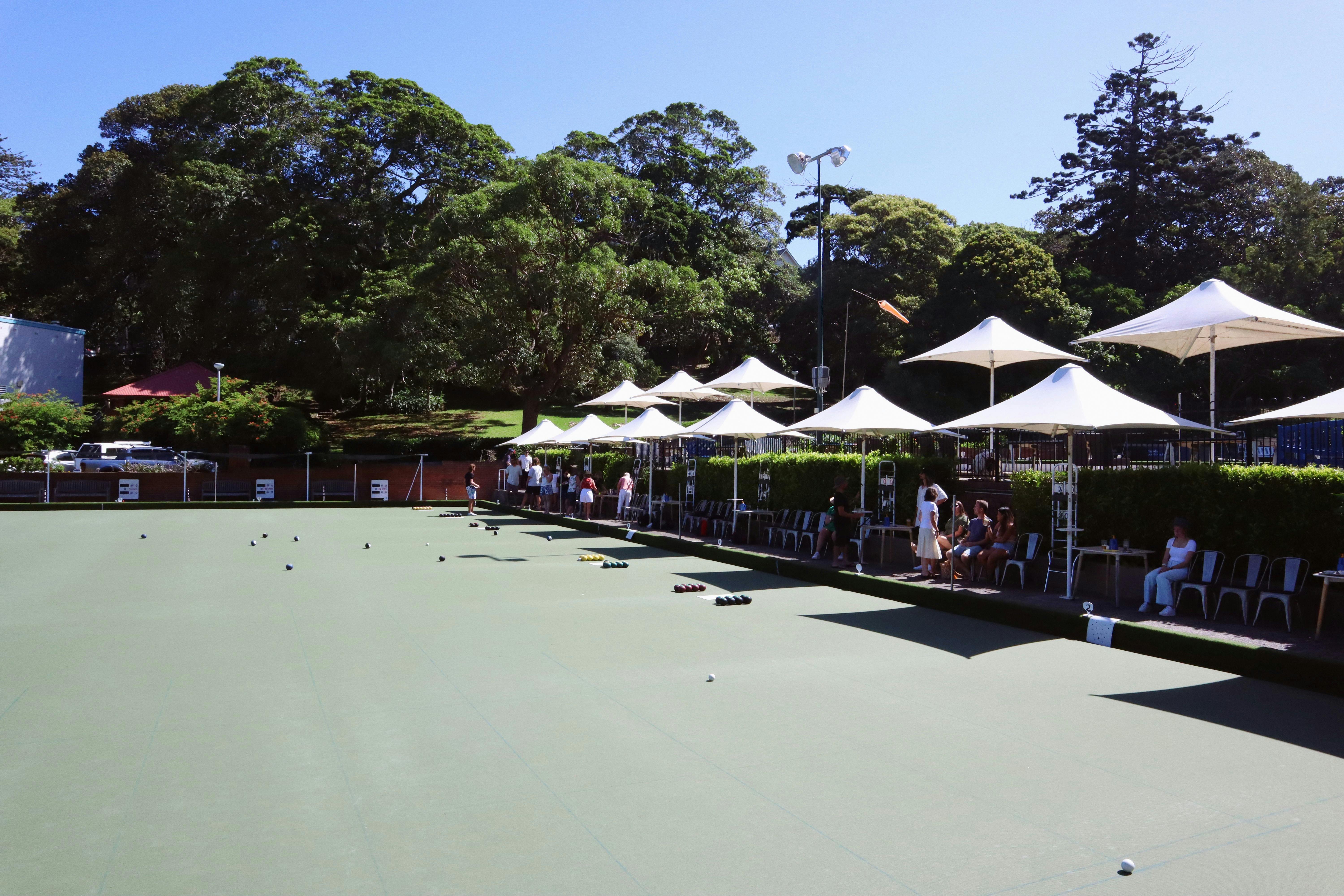 A busy barefoot bowling green on a sunny day.