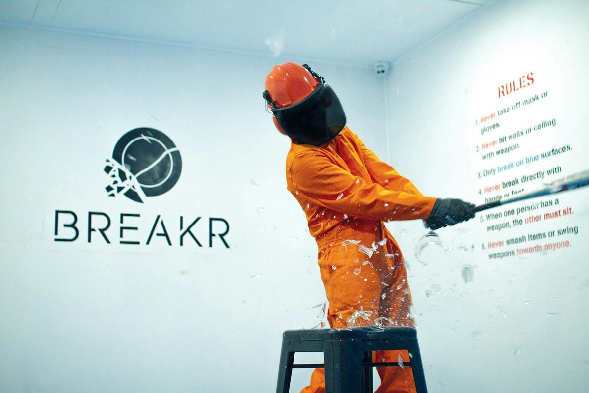 Someone in protective gear, smashing glass with a bat