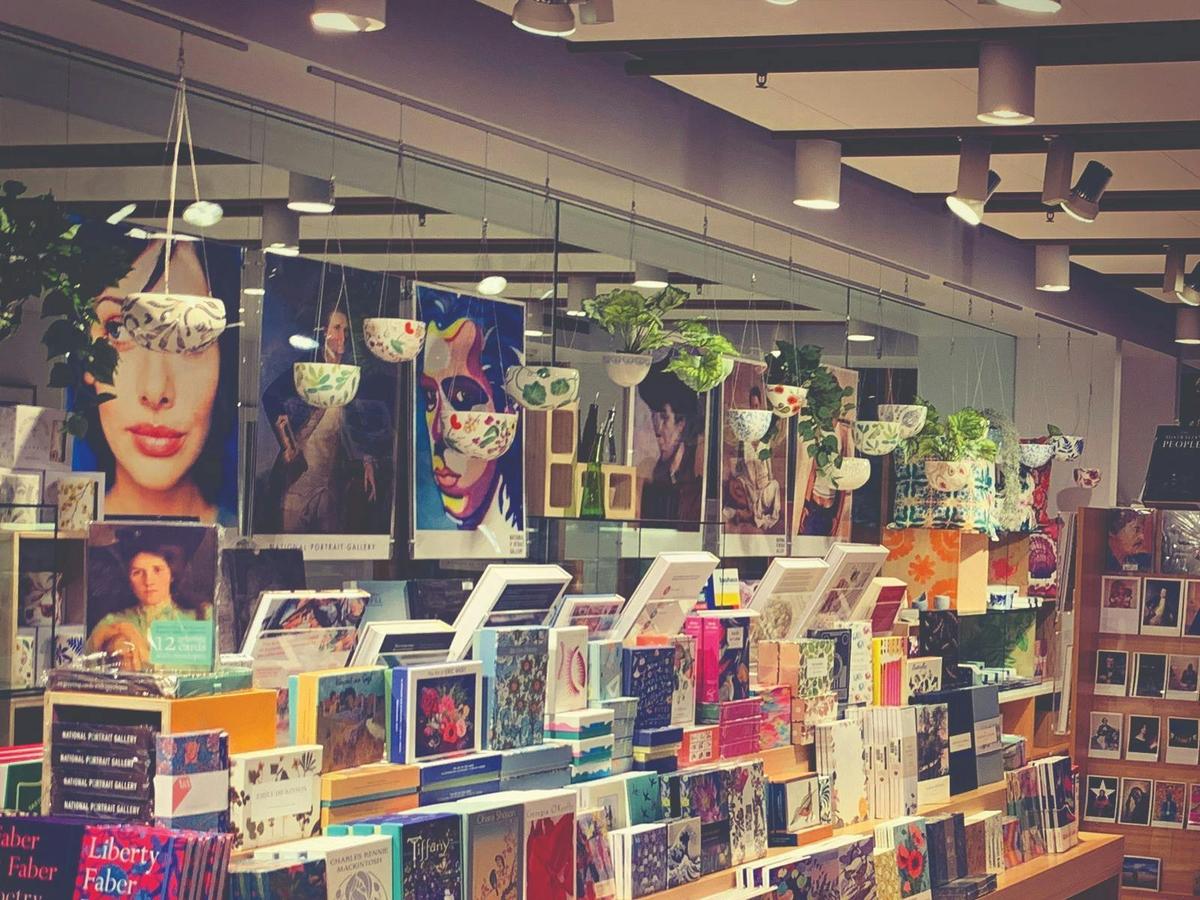 Posters of portraits from collection in the background with rows of boxed stationery