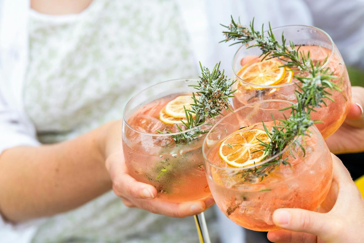 Three gin and tonics clink together to cheers