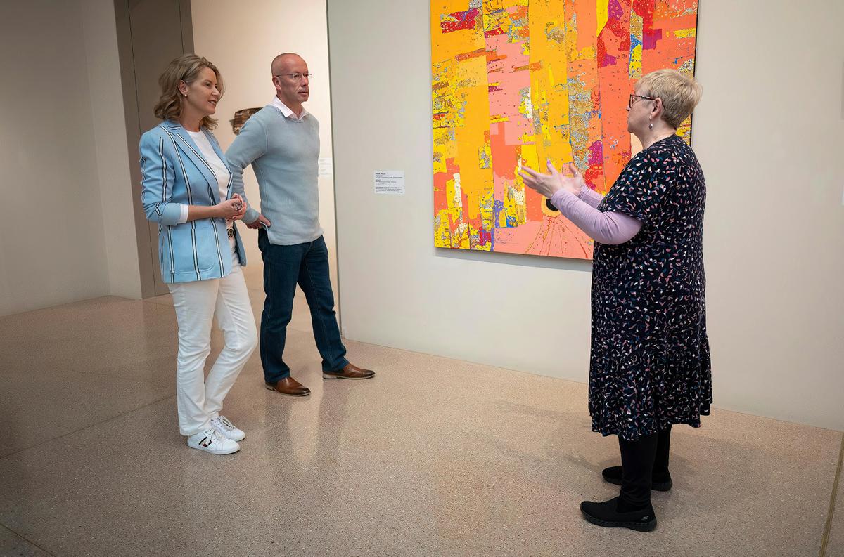 A gallery curator and couple standing in front of an artwork
