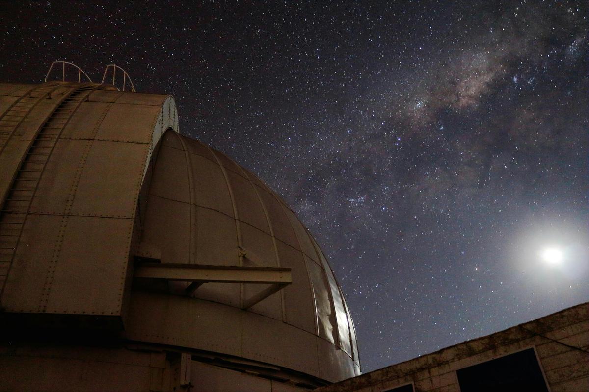A telescop dome with the Moon and Milky Way Galaxy.