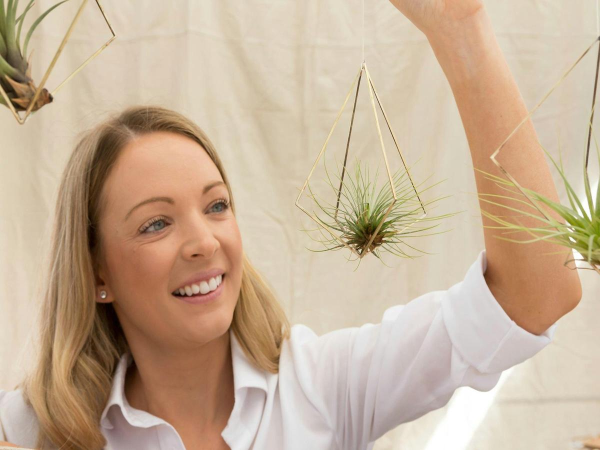 A visitor with a stallholders hanging air plant at the Old Bus Depot Markets
