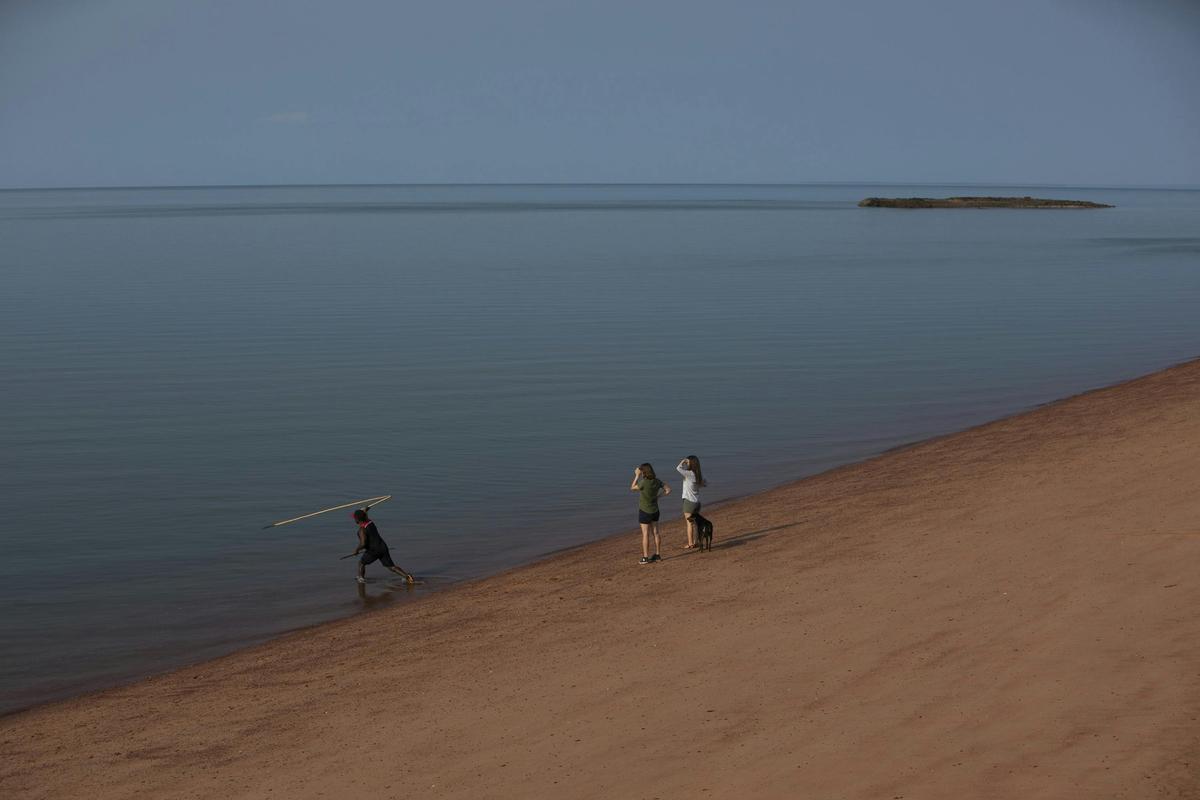 Aboriginal man throwing a spear into the sea from the shore in East Arnhem Land