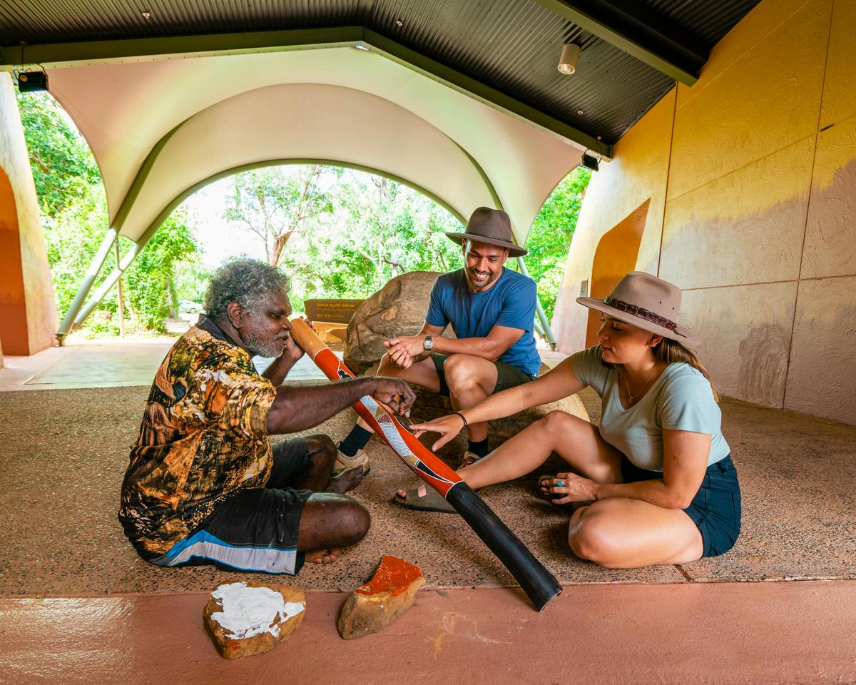 Couple with artist painting a didgeridoo