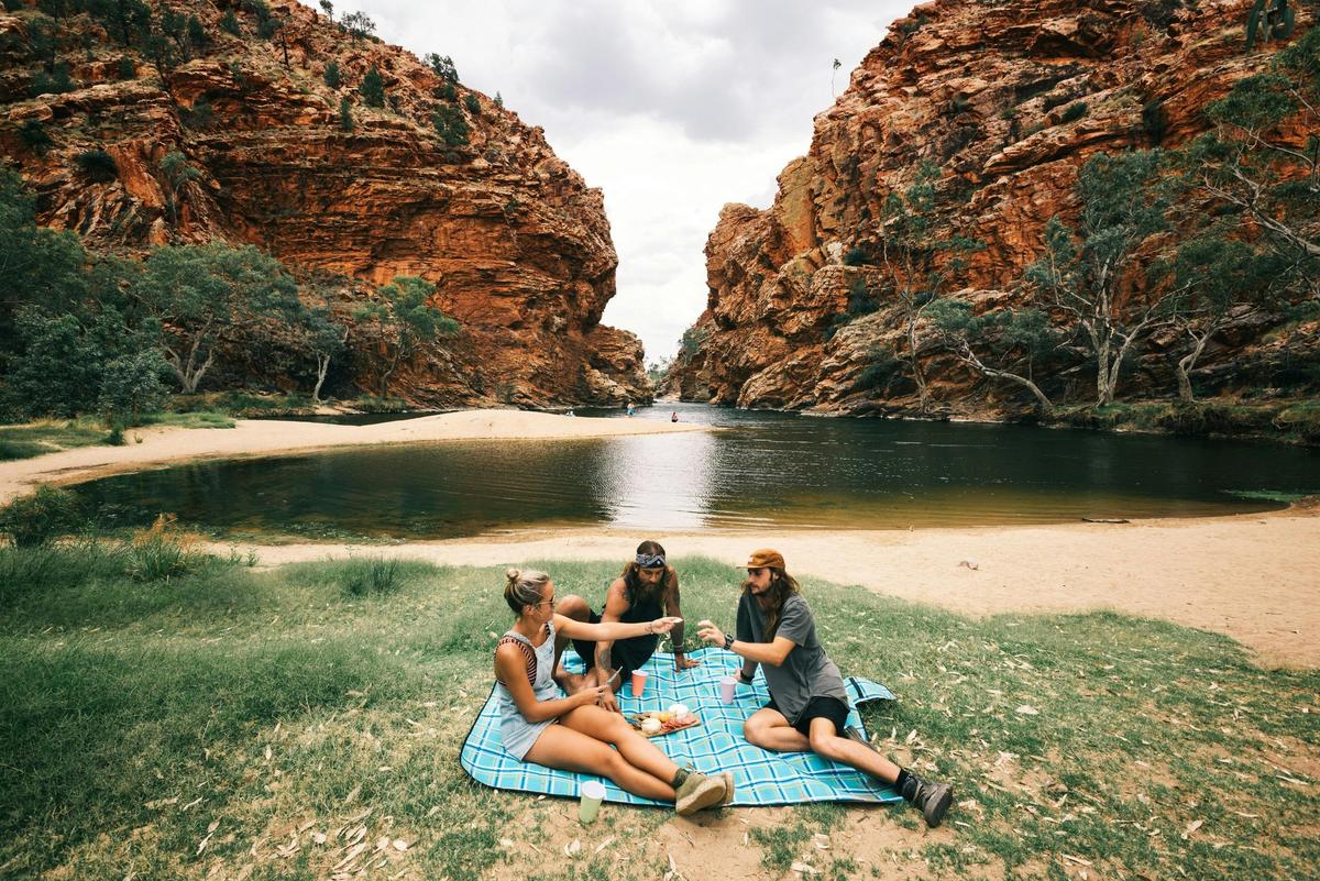 A group of friends having a picnic on the grass next to Ellery Creek Big Hole