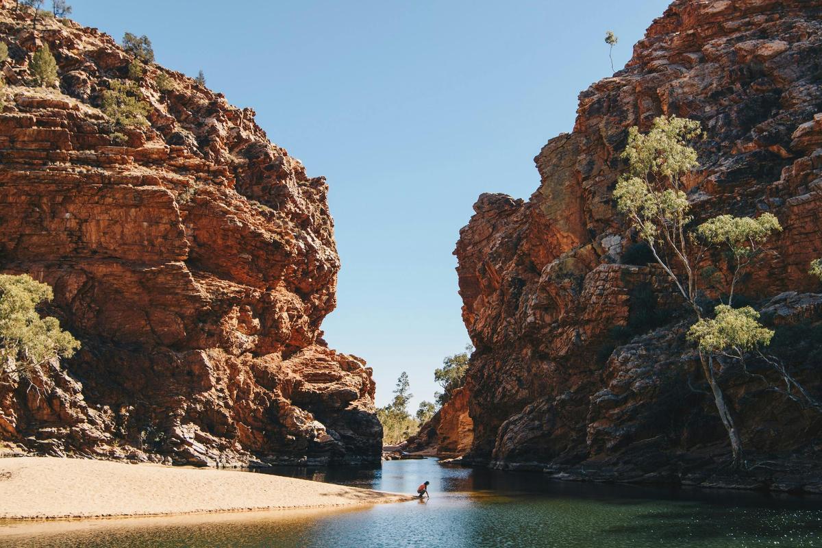 A lady tests the temperature of the water at Ellery Creek Big Hole