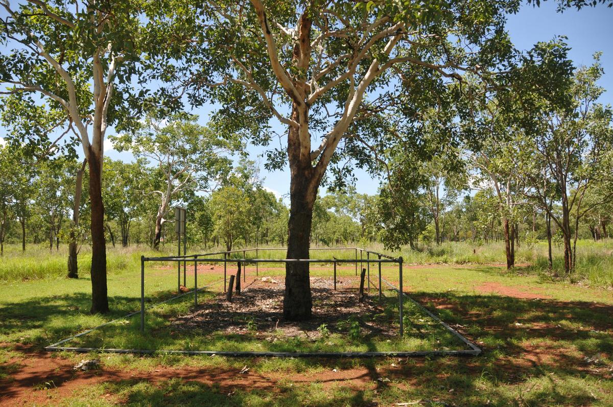 Cemetery site defined by a concrete kerb and steel fence. A shade shelter is outside the cemetery.