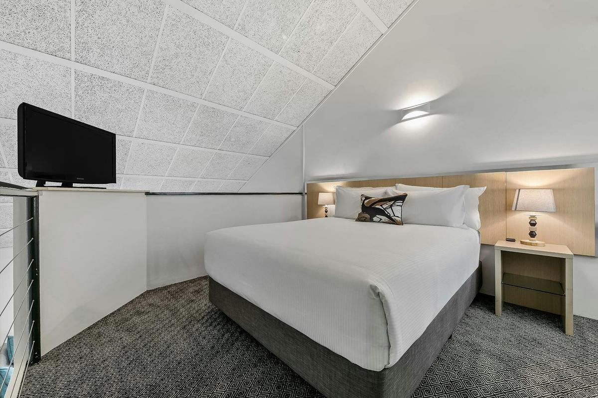 Loft apartment bedroom with queen bed and TV.