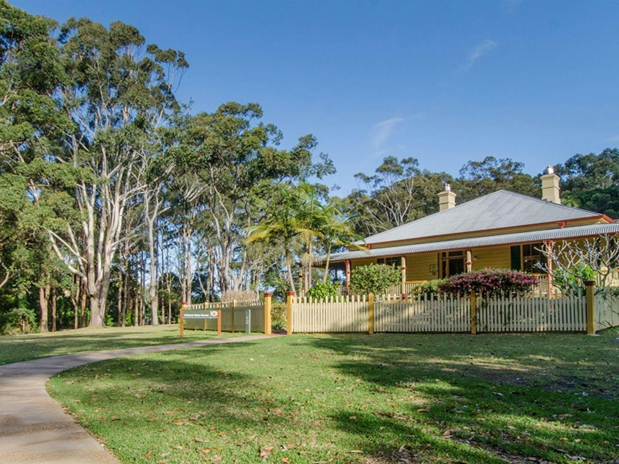 Roto House and the path leading up to it, surrounded by green lawn, gum trees and blue sky, Roto