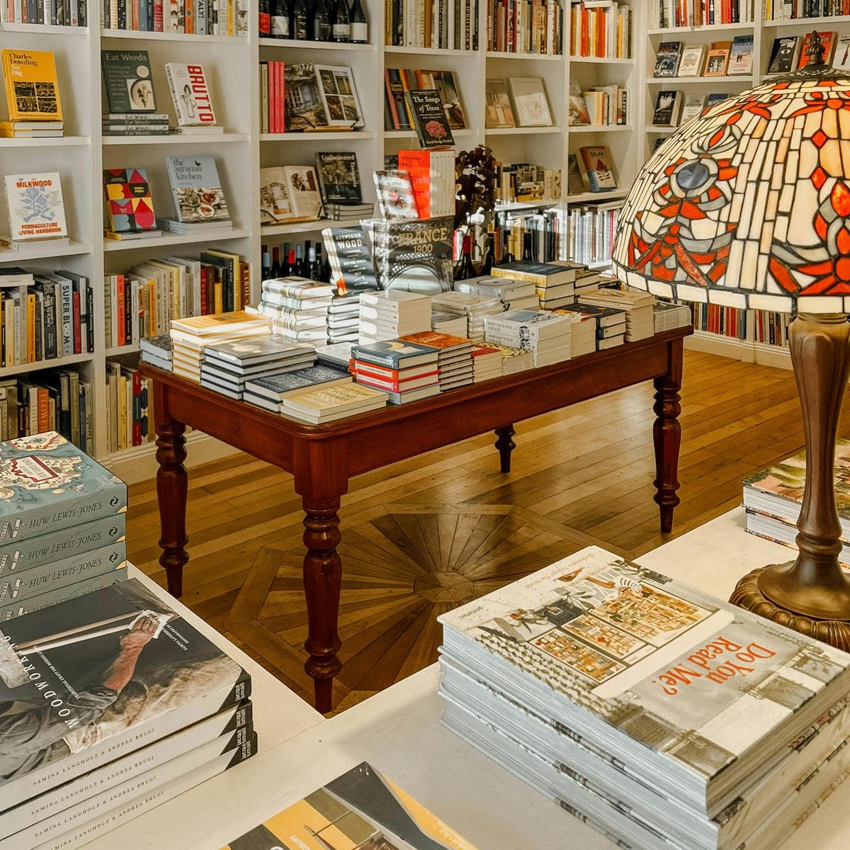 A central table of beautifully stacked books beneath warm light.