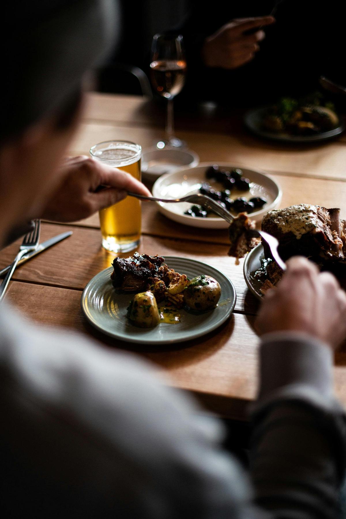 A man pulling apart a slow cooked lamb dish at a table