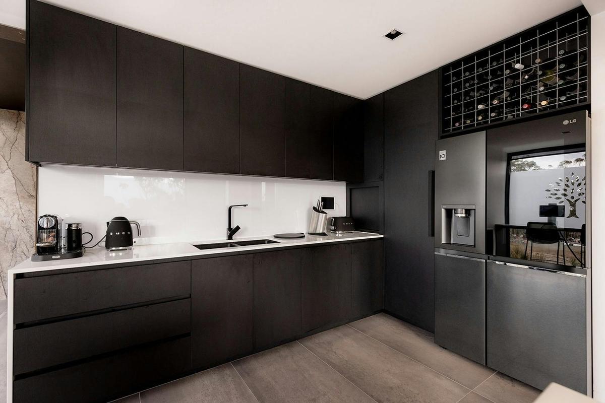 Sleek, fully-equipped black kitchen with modern appliances and marble splashback.