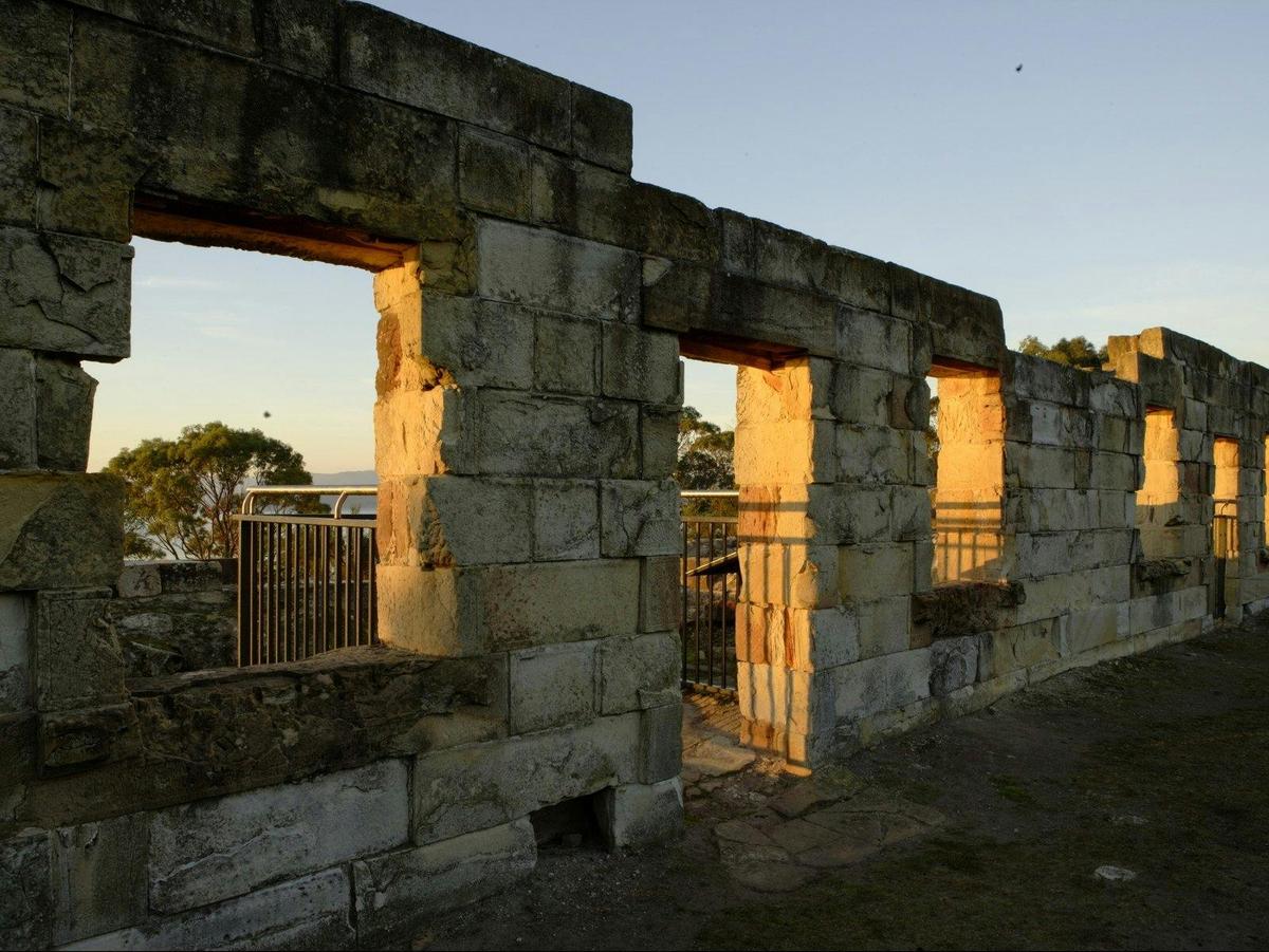 Warm sunset beams through the rough stone wall frames of the empty cell windows
