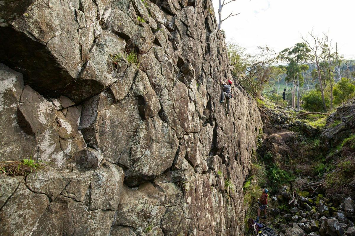 A climber on a sheer and textured rock face.