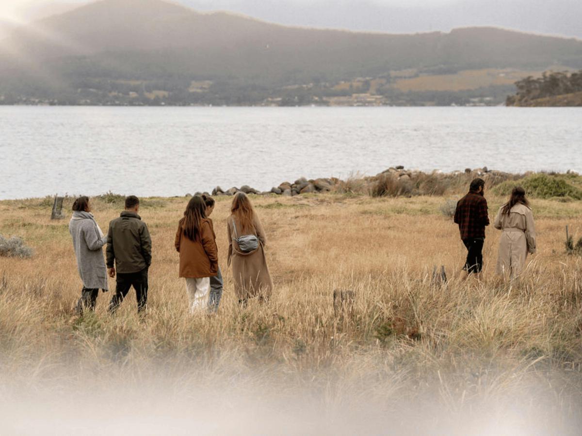 Group of guests walking through coastal grassland toward the channel.