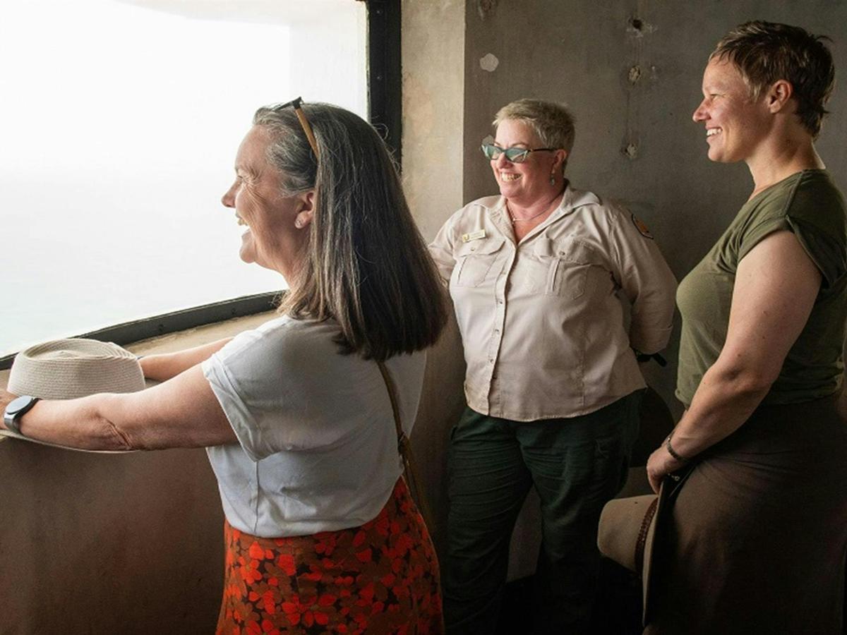 Visitors pause to enjoy the view from a curved lighthouse window, as they climb the lighthouse