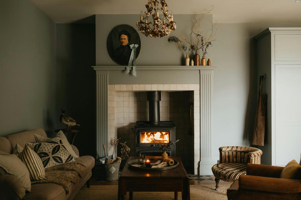 Fireplace living room with wood heater, antiques, and soft layered interiors.
