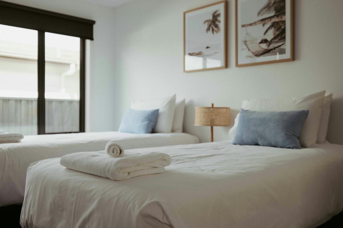 The second bedroom features two long single beds with electric blankets and a sliding wardrobe.