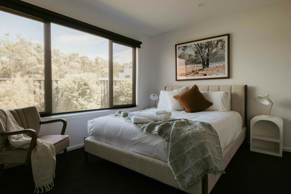 Relax in the master bedroom with a queen bed, plush pillows, 55-inch TV, walk-in robe, and ensuite.