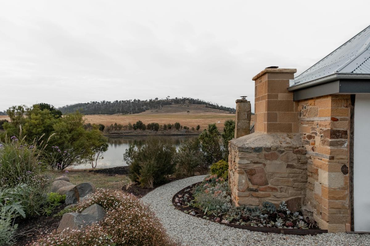 Landscaped gardens bridge the space between sandstone chimneys and the Carlton river