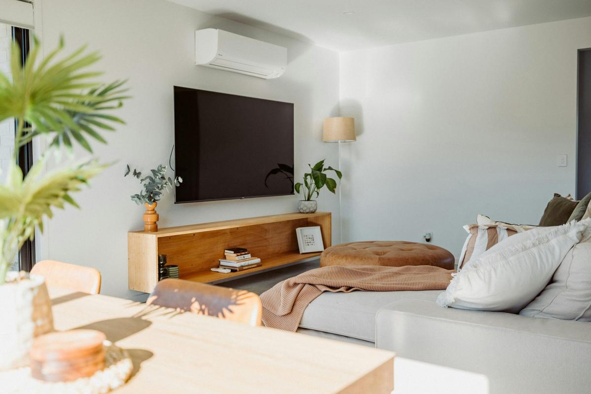 The open-plan living area features a comfy couch, smart TV, and a 6-seater dining table.